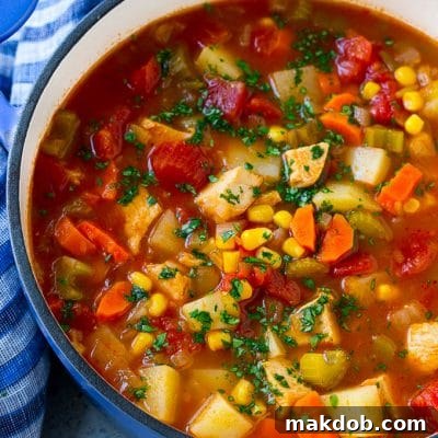 A pot of Mexican chicken soup with colorful veggies and potatoes, all topped with cilantro.