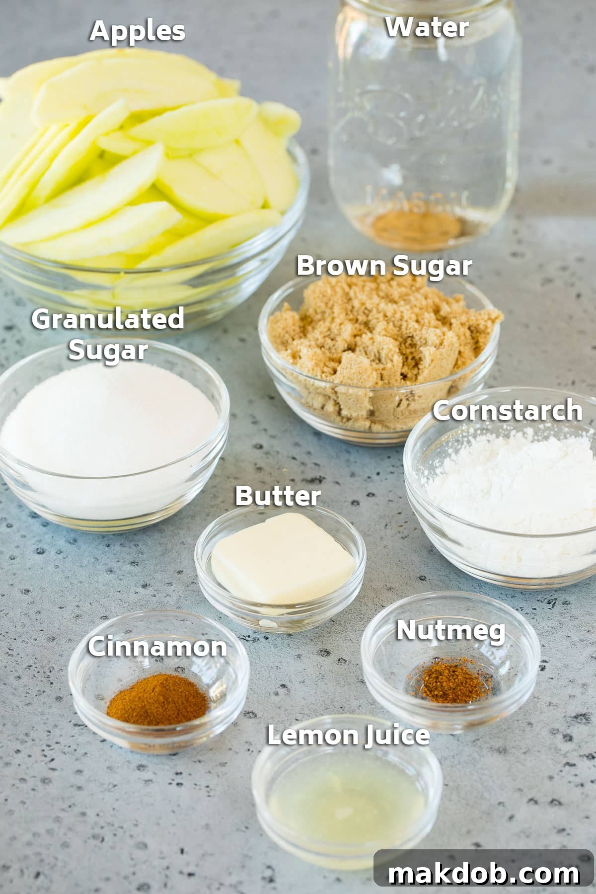 Bowls of essential ingredients including sliced apples, sugars, and spices, prepared for homemade apple pie filling.