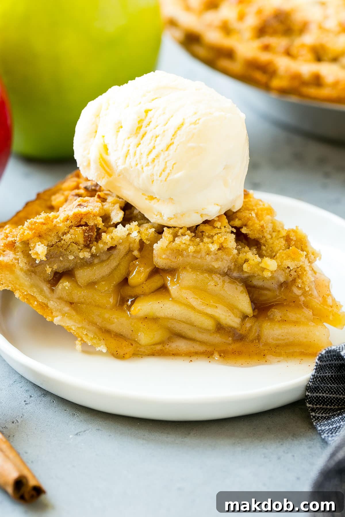 A generous slice of warm apple pie, beautifully topped with a scoop of melting vanilla ice cream, showcasing the rich filling.
