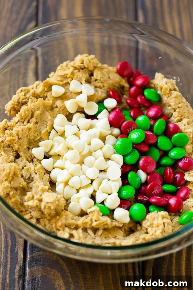 Christmas Monster Cookies Recipe | Oatmeal Cookies | Peanut Butter Cookies | M&M's Cookies #baking #cookies #dessert #peanutbutter #chocolate #dinneratthezoo #christmas #sprinkles Cookie dough with red and green M&M's and white chocolate chips.