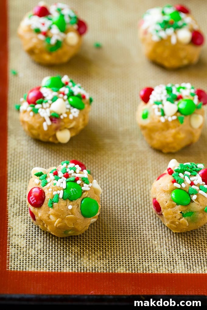 Christmas Monster Cookies Recipe | Oatmeal Cookies | Peanut Butter Cookies | M&M's Cookies #baking #cookies #dessert #peanutbutter #chocolate #dinneratthezoo #christmas #sprinkles Balls of cookie dough on a baking sheet.