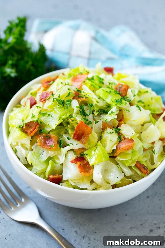 A bowl of fried cabbage topped with bacon and parsley.