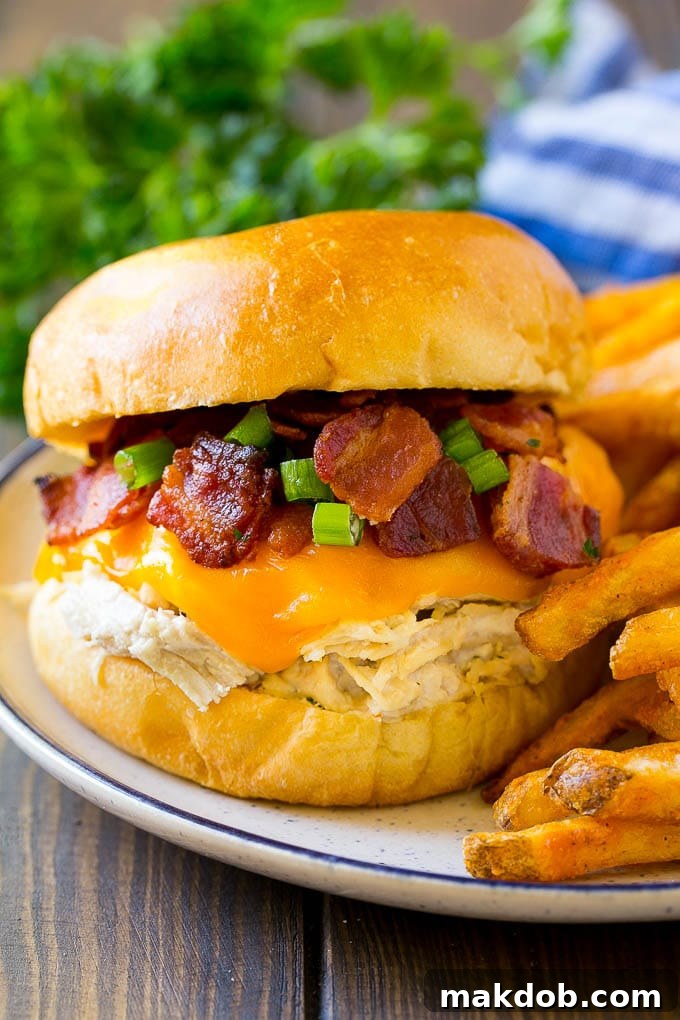 A crack chicken sandwich topped with cheese, bacon and green onions.