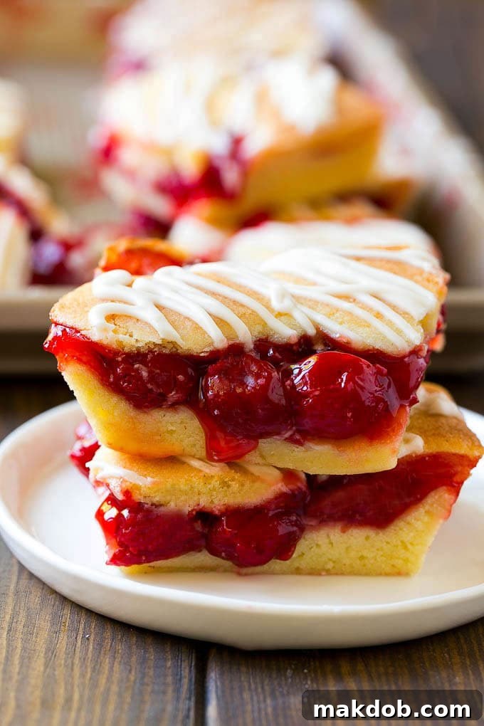 Cherry Bars Recipe | Cherry Pie Bars | Cherry Cookies | Bar Cookies #cookies #bars #cherry #baking #dessert #sweets #dinneratthezoo Two cherry bars on a plate with a pan of bars in the background.