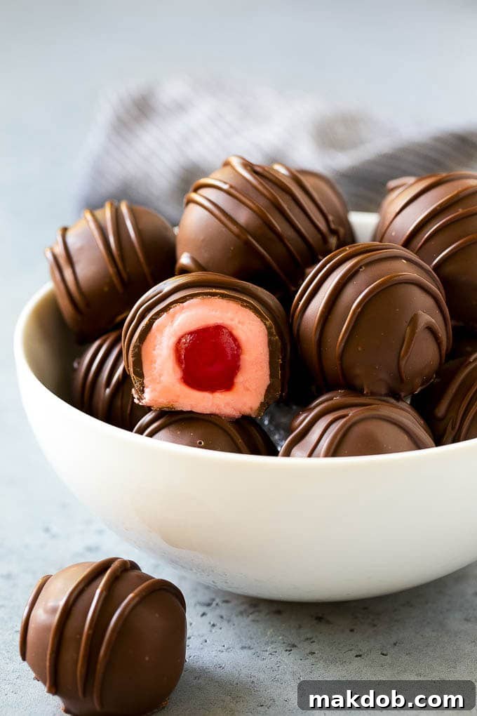 Chocolate Covered Cherries Recipe | Cherry Cordials | Cherry Candy #chocolate #candy #dessert #cherry #sweets #dinneratthezoo A bowl of chocolate covered cherries with one cut open.