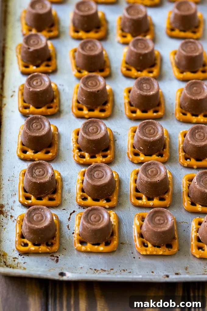 Rolo Pretzels Recipe | Chocolate Pretzels | Caramel Pretzels | Holiday Candy #christmas #baking #dessert #candy #chocolate #caramel #pretzels #dinneratthezoo Squares of pretzels topped with unwrapped Rolo candies on a baking sheet, ready for the oven.
