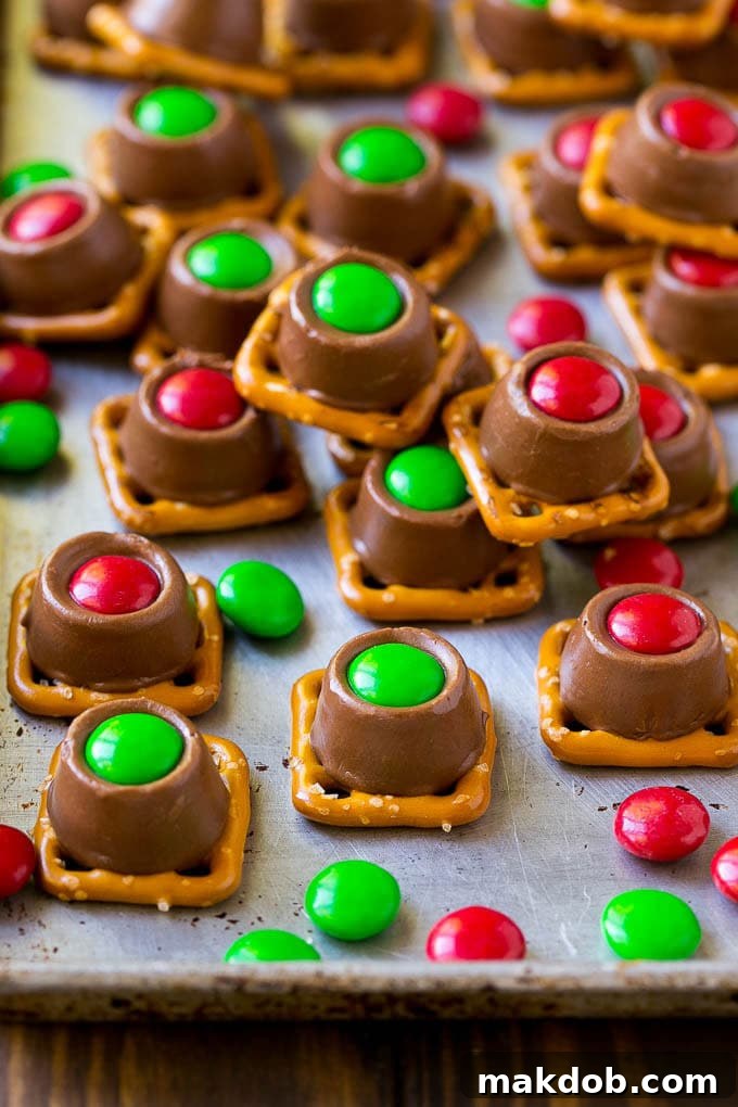 Rolo Pretzels Recipe | Chocolate Pretzels | Caramel Pretzels | Holiday Candy #christmas #baking #dessert #candy #chocolate #caramel #pretzels #dinneratthezoo A close-up of finished Rolo pretzels on a baking sheet, featuring red and green M&M's.