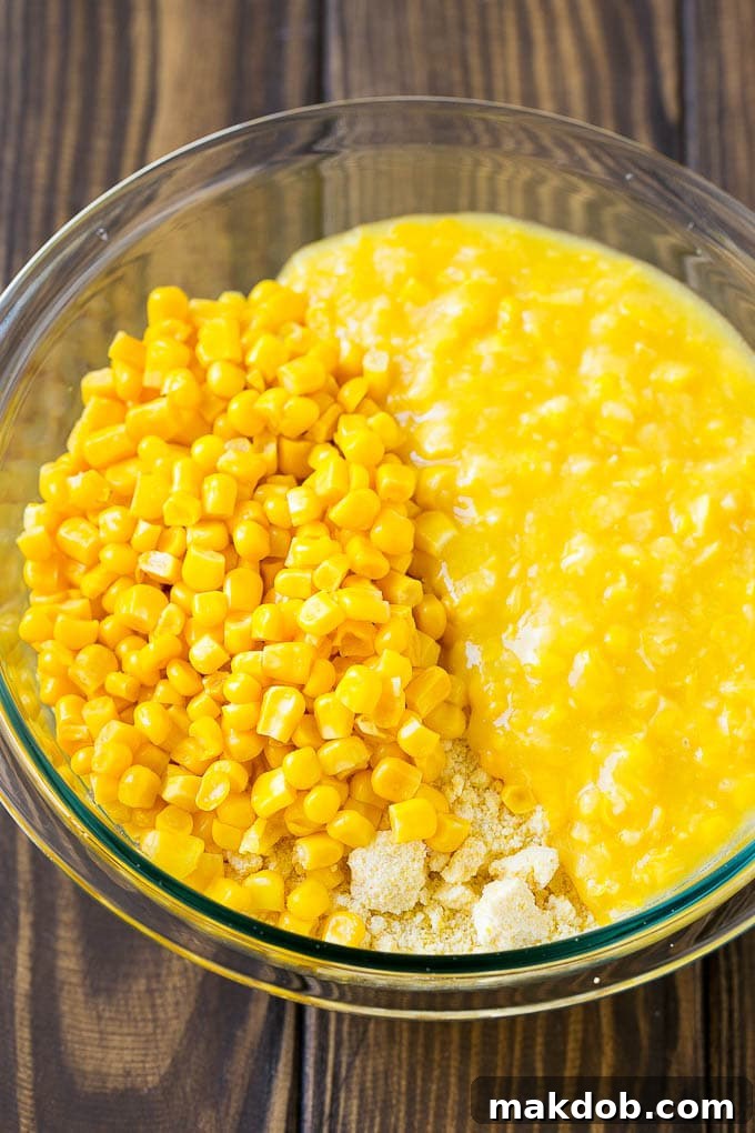 Loaded Corn Casserole Recipe | Easy Corn Casserole | Bacon Corn Casserole | Corn Pudding #corn #casserole #bacon #cheese #sidedish #thanksgiving #dinner #dinneratthezoo A mixing bowl filled with the base ingredients for corn casserole: cornbread mix, whole kernel corn, and creamed corn.