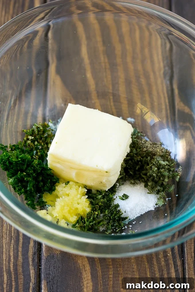 Softened butter, minced garlic, fresh herbs, and seasonings in a mixing bowl, ready to be combined for the turkey rub.