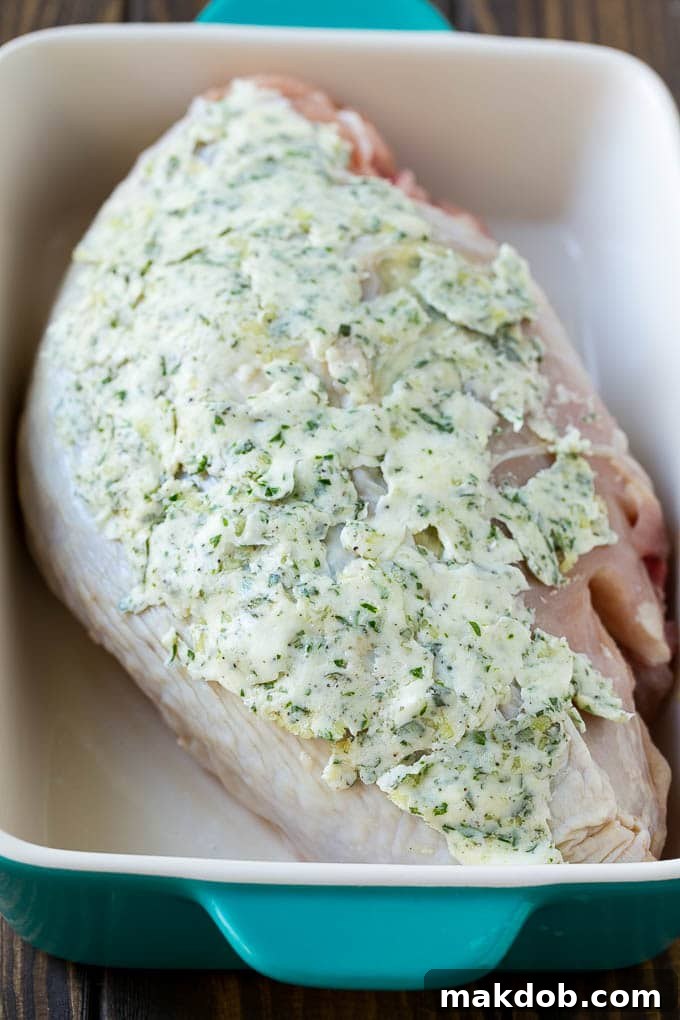 A turkey breast generously coated with savory garlic and herb butter, ready for roasting.