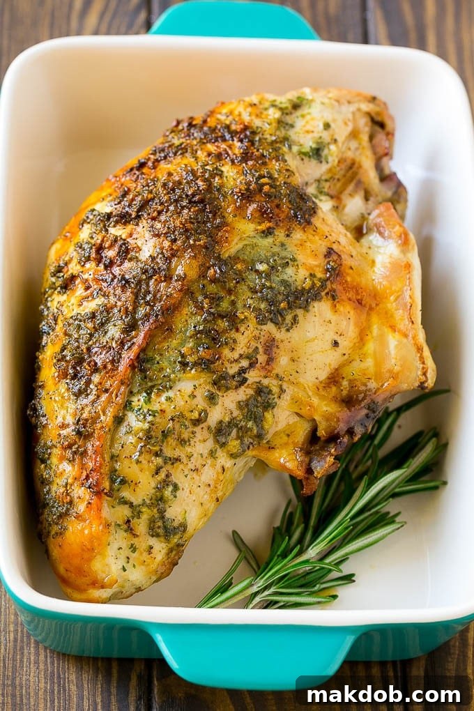 A beautifully roasted turkey breast, golden brown and glistening, resting in a baking dish with pan juices.