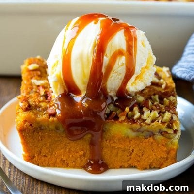 A slice of pumpkin dump cake topped with ice cream and caramel sauce.