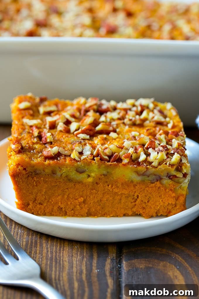 A neat slice of pumpkin dump cake, revealing its creamy pumpkin base and golden pecan-studded topping, served on a plate.