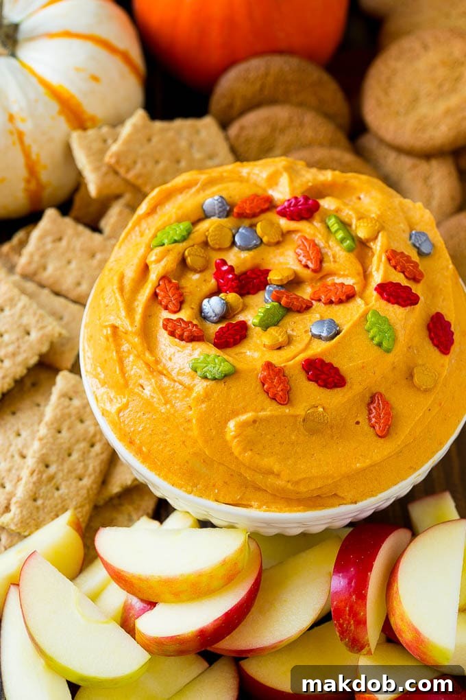 Easy 5-Minute Pumpkin Dip Recipe for Fall Desserts & Appetizers Fluffy pumpkin dip served elegantly with crisp red apple slices, classic graham crackers, and spicy gingersnap cookies, all arranged on a festive autumn platter.