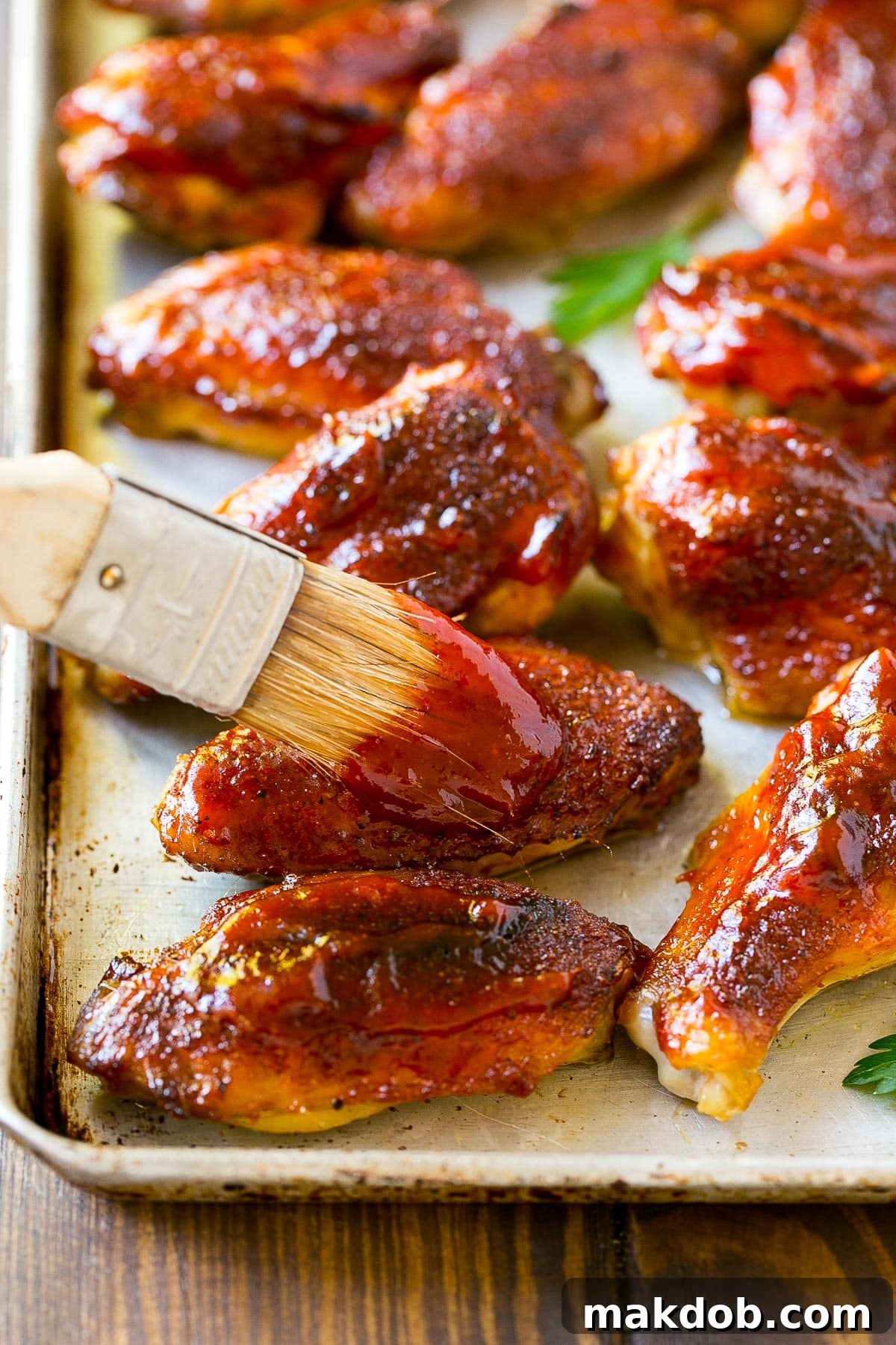 Signature Backyard BBQ Sauce 5 Homemade BBQ sauce being generously brushed onto grilled chicken wings, creating a delicious glaze.
