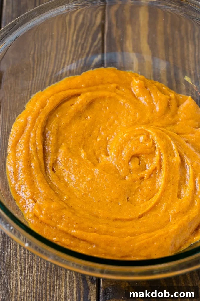 A bowl filled with rich, orange pumpkin chocolate chip muffin batter.