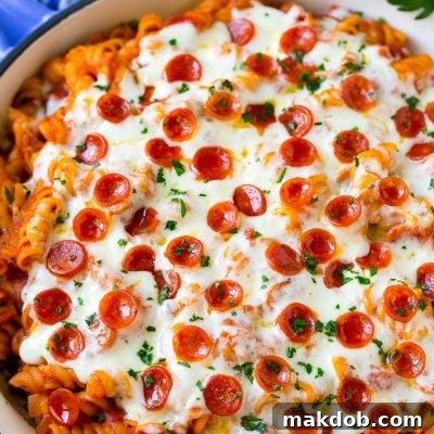 Pizza pasta in a skillet topped with melted cheese and pepperoni, ready to serve.