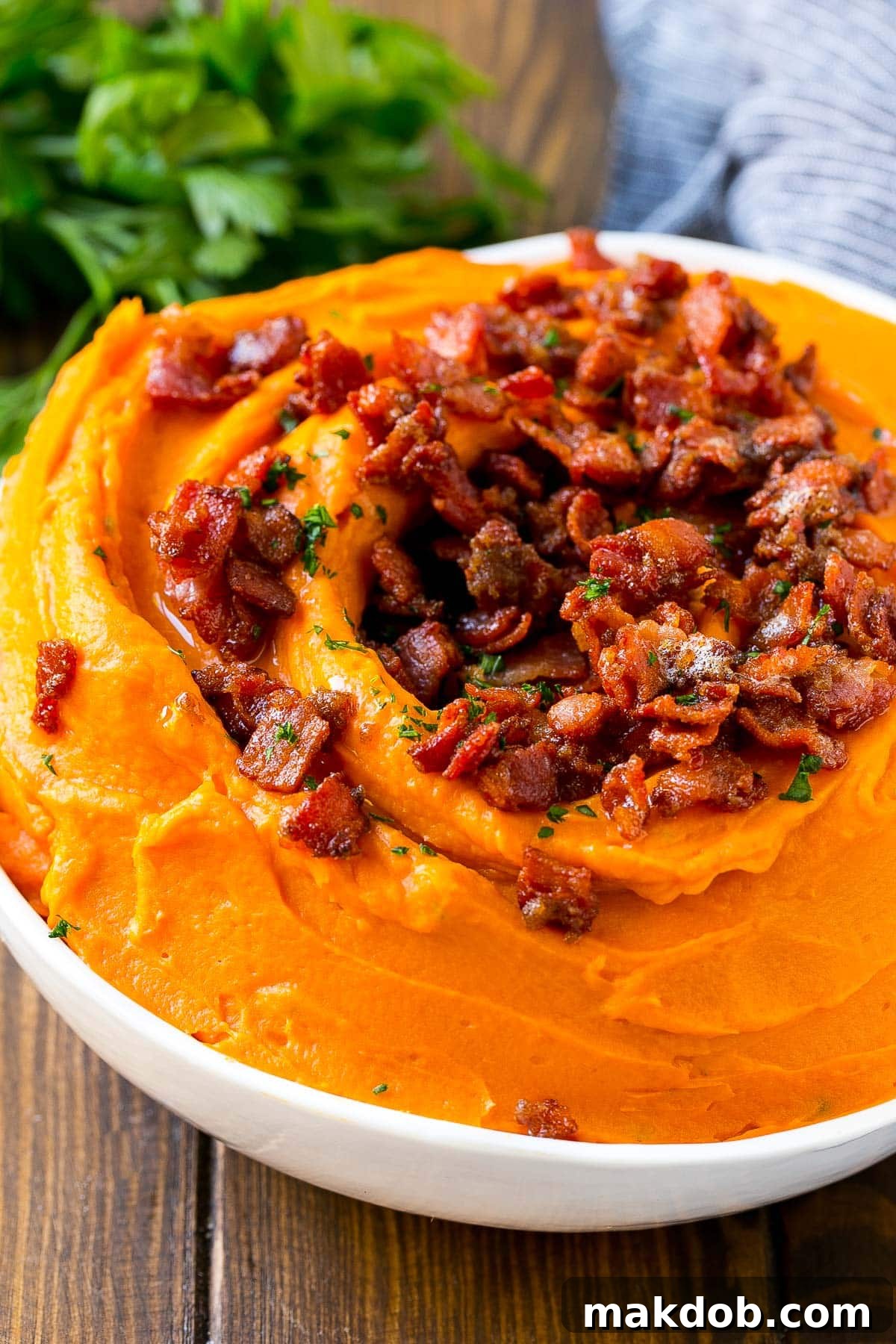 A bowl of pureed sweet potatoes topped generously with crispy bacon bits.