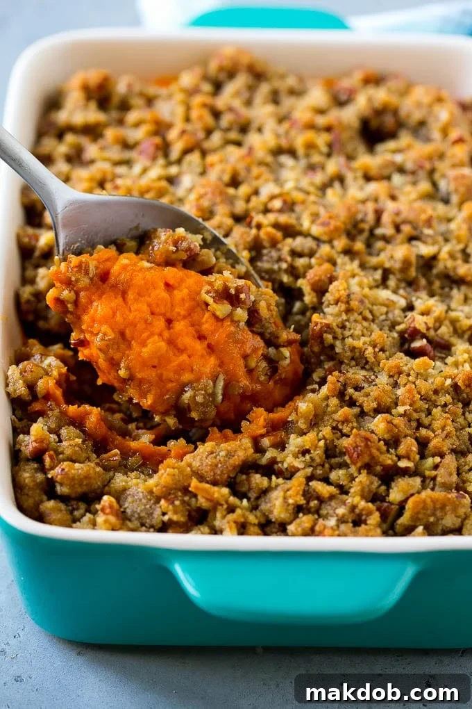 Ruth's Chris Sweet Potato Casserole Recipe | Sweet Potato Casserole | Mashed Sweet Potatoes #sweetpotatoes #casserole #thanksgiving #christmas #holidays #dinner #dinneratthezoo #sidedish Ruth's Chris sweet potato casserole with a serving spoon in it.