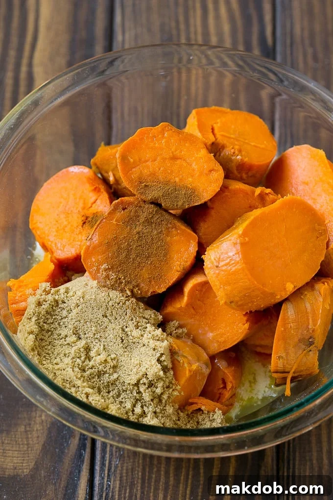 Sliced sweet potatoes with brown sugar, butter, and spices, ready for mashing.