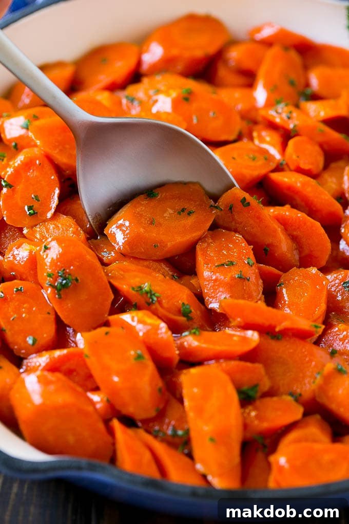 Glazed carrots in a skillet with a serving spoon.