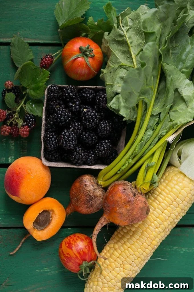 A vibrant selection of fresh farmer's market produce, including corn on the cob, red beets, ripe apricots, plump tomatoes, and sweet blackberries.