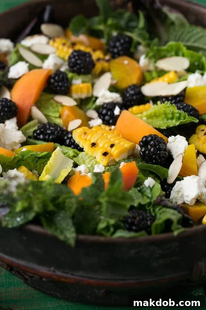 A large bowl of fresh, crisp lettuce, generously topped with an assortment of vibrant berries, golden corn kernels, crumbled feta cheese, and juicy apricot slices, awaiting the dressing.