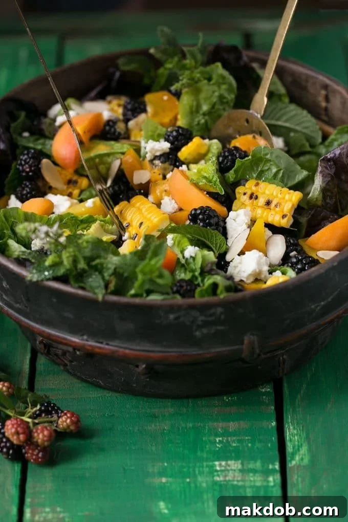 Salad tongs gently tossing together the fresh blackberry salad, ensuring every ingredient is perfectly coated with the creamy apricot dressing.