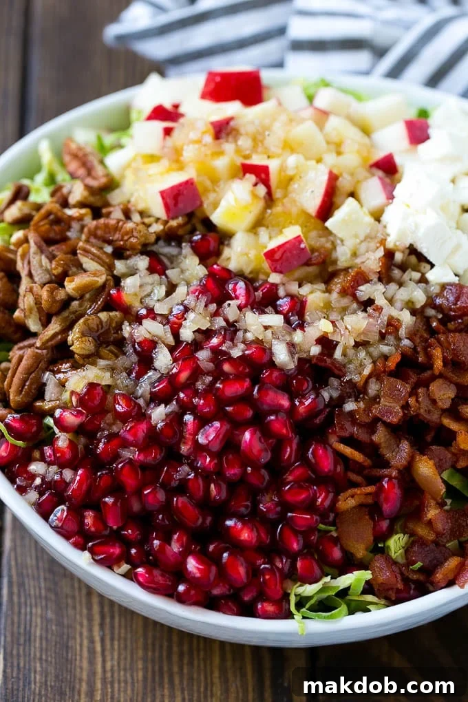 Dressing poured on top of salad that contains sprouts, pomegranate seeds, pecans and bacon.
