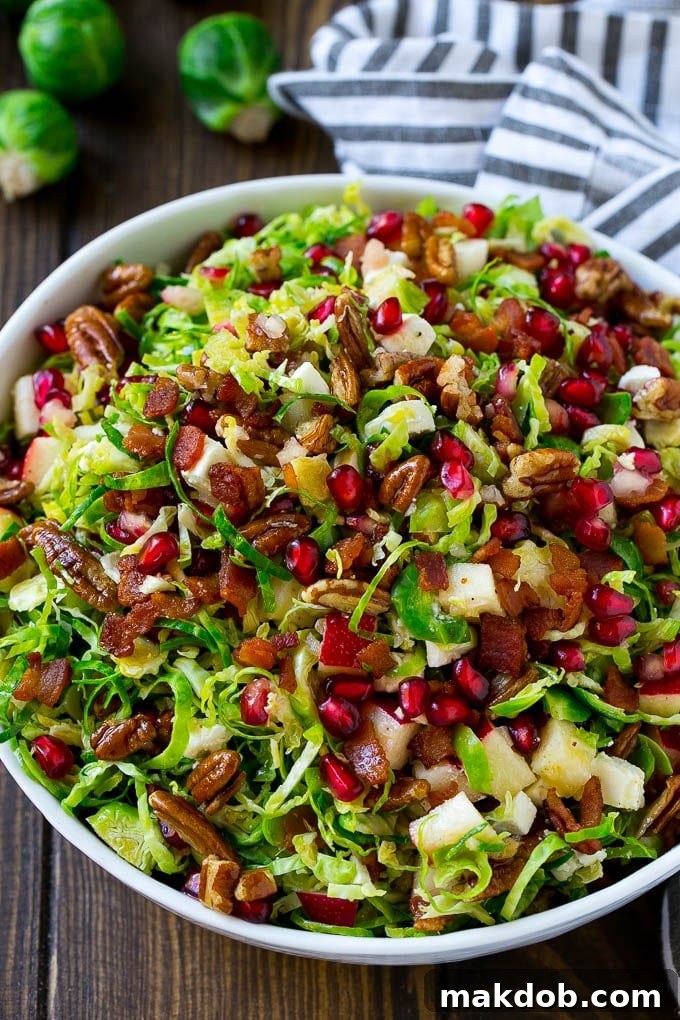A bowl of salad made with pomegranate, bacon and apples.