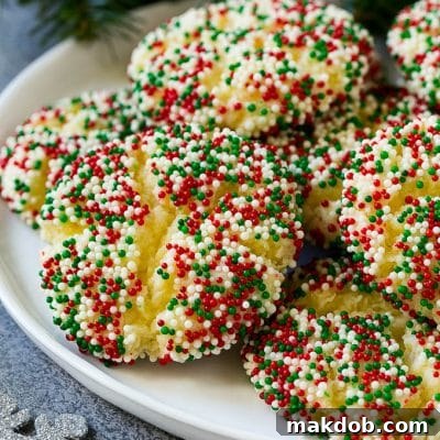 A plate of gooey butter cookies covered in holiday sprinkles, showcasing their soft, cracked texture.