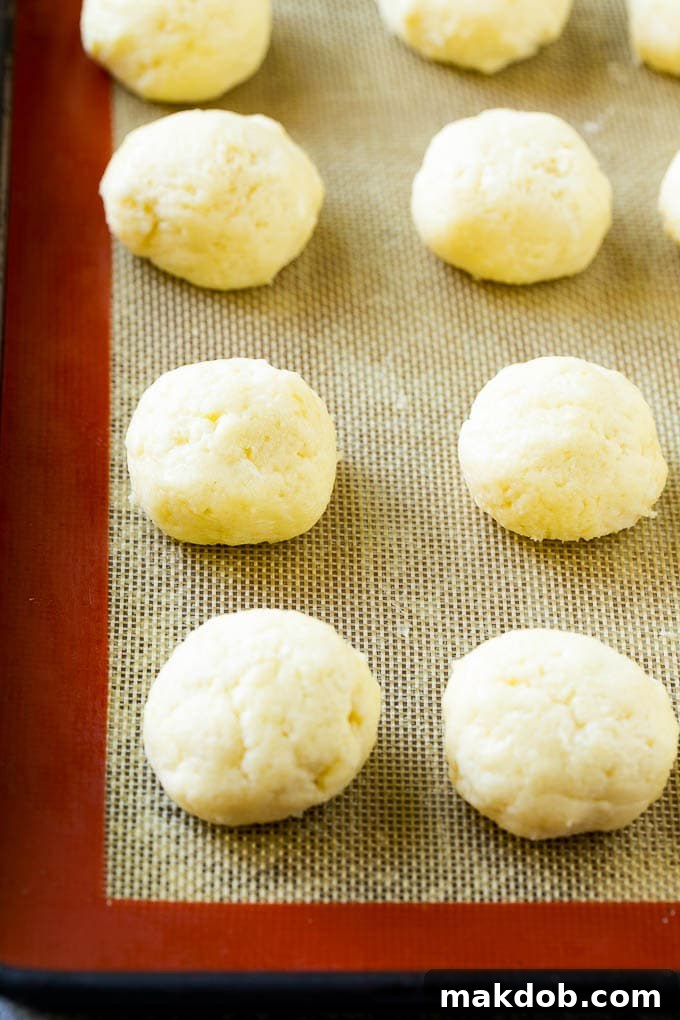 Balls of gooey butter cookie dough resting on a baking sheet, ready for the oven.