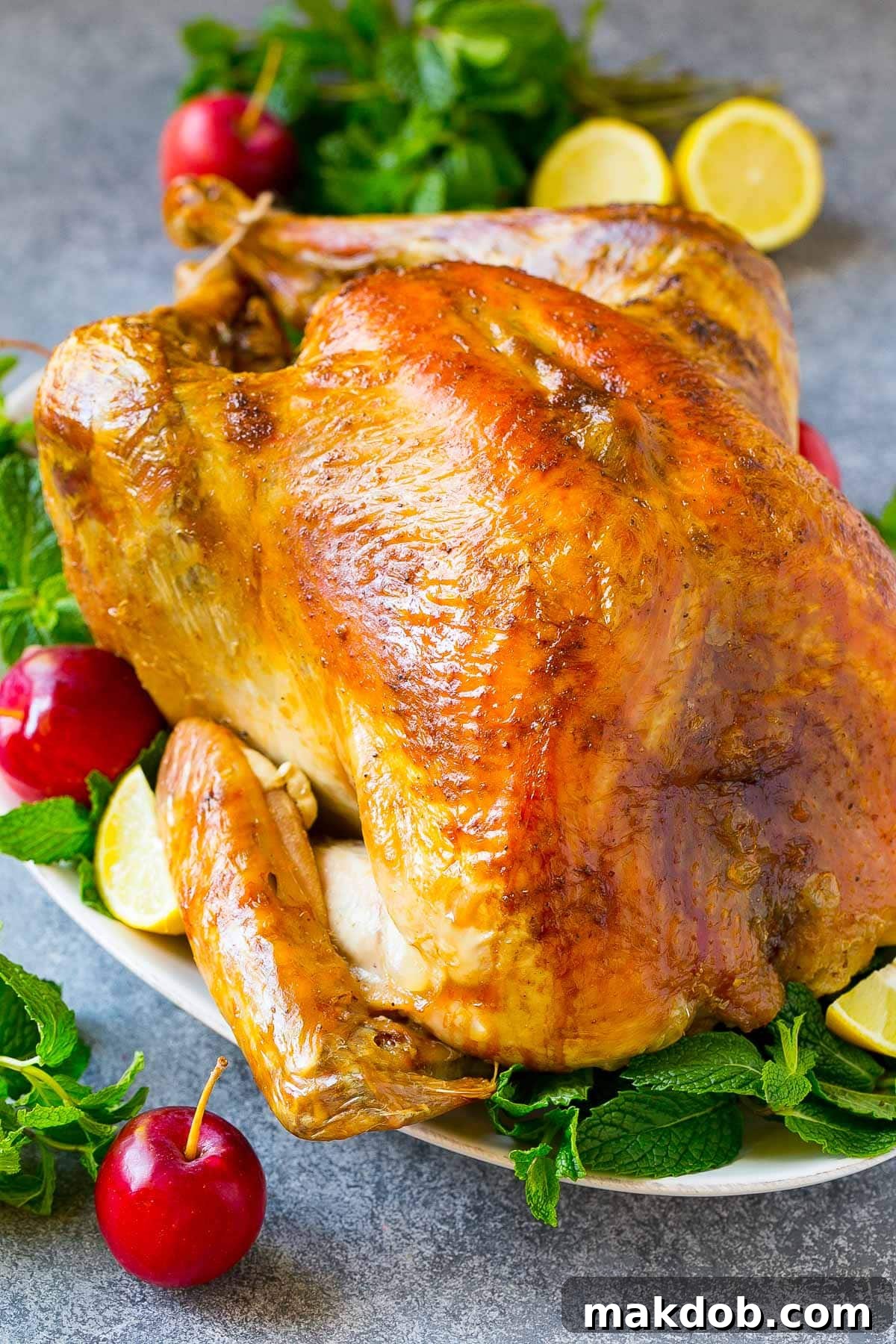 A beautifully roasted turkey, golden brown and perfectly cooked, resting on a serving platter with herbs.