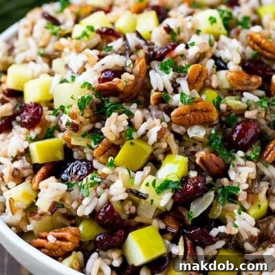 A serving bowl of rice pilaf made with wild rice, apples, cranberries and pecans.