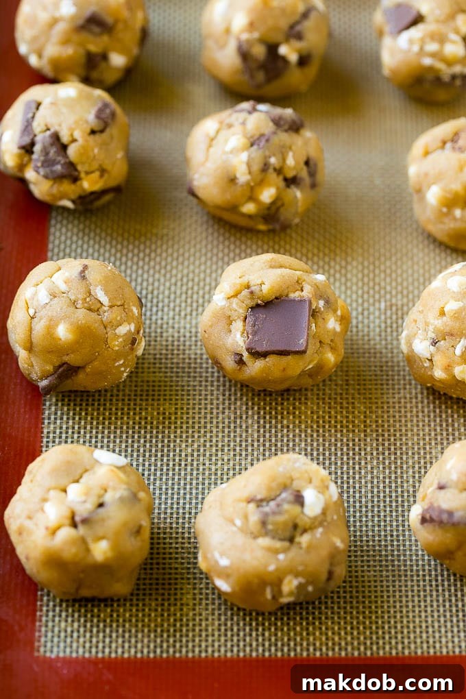 Balls of S'mores cookie dough neatly arranged on a baking sheet, ready for the oven.
