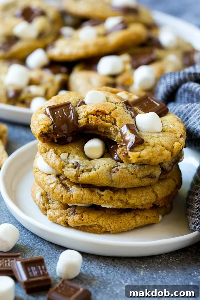 A stack of S'mores cookies with a bite taken out of one, revealing the gooey interior.