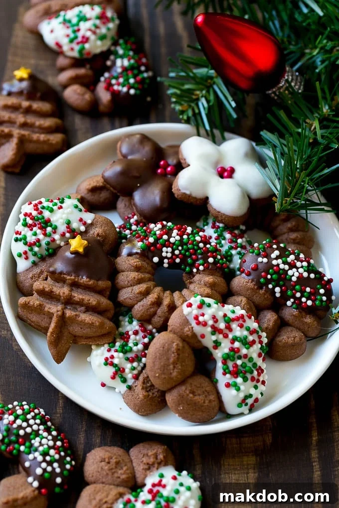 Chocolate spritz cookies coated in sprinkles on a serving plate, glistening and festive.