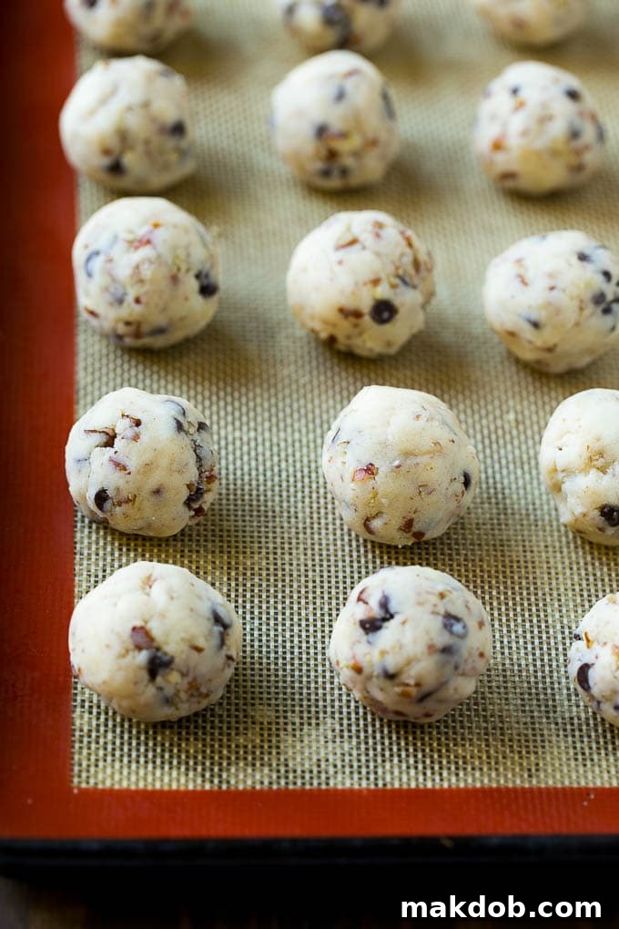 Snowball Cookies Recipe | Mexican Wedding Cookies | Russian Tea Cakes #cookies #pecan #chocolate #baking #dessert #christmas #dinneratthezoo Uniform balls of snowball cookie dough neatly arranged on a baking sheet, prepped and ready to be baked in the oven.