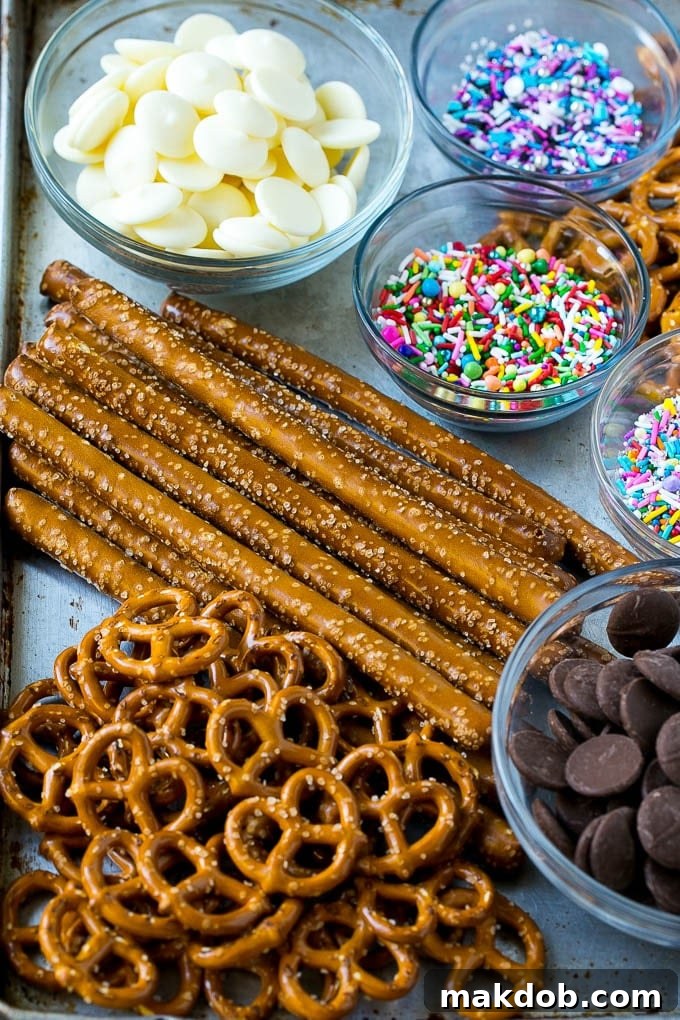 Chocolate Covered Pretzels Recipe | Sprinkle Pretzels | No Bake Dessert #pretzels #chocolate #christmas #sprinkles #candy #dinneratthezoo Ingredients including candy melts and sprinkles on a sheet pan.