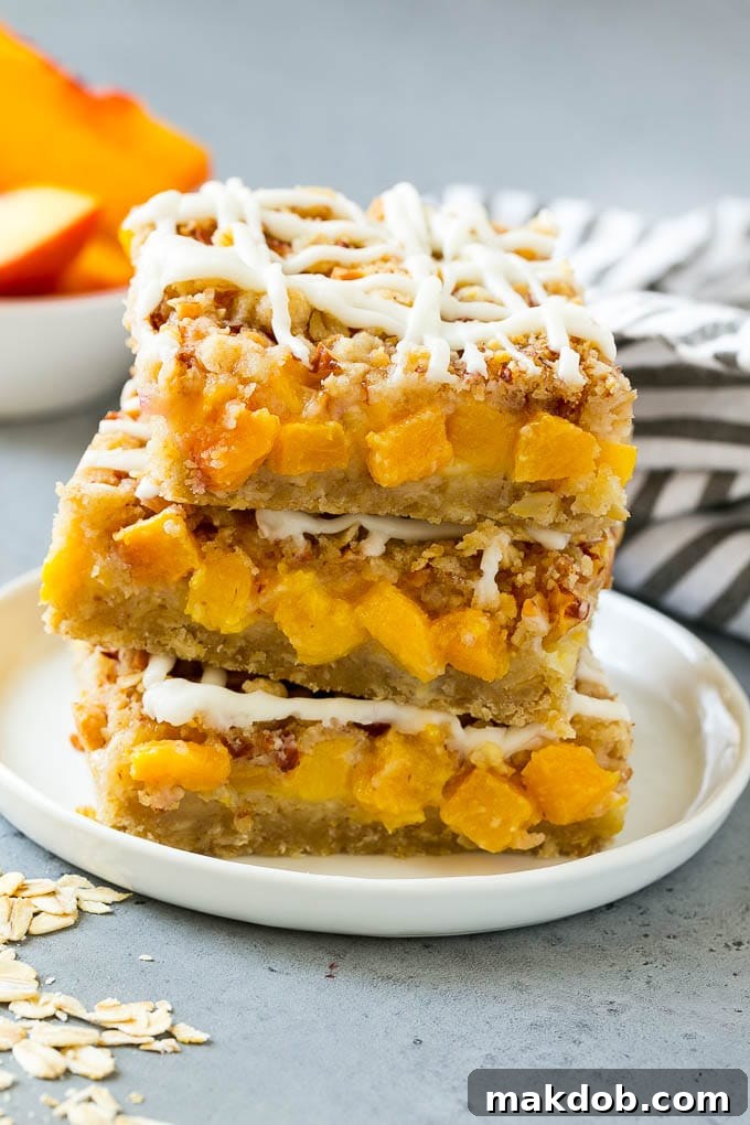 Delicious Peach Crumble Bars with Vanilla Glaze A beautifully arranged stack of golden-brown peach crumble bars, generously topped with a shimmering vanilla glaze, ready for serving.