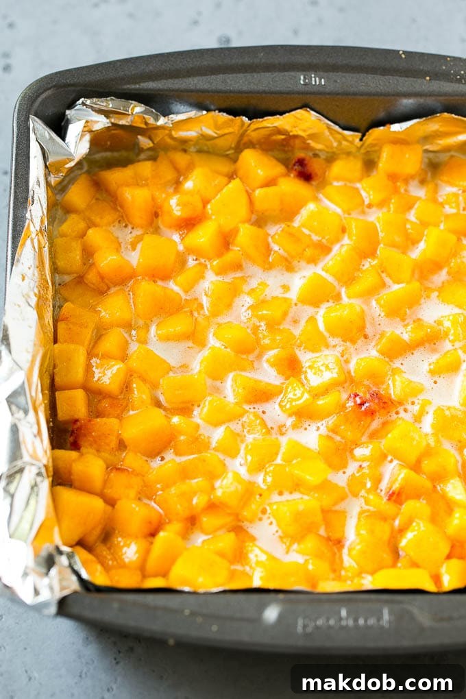 Sweet Peach Filling Layer for Crumble Bars A vibrant peach filling, glistening and sweet, spread generously over the golden-brown oatmeal crust in a square pan, awaiting its streusel topping.
