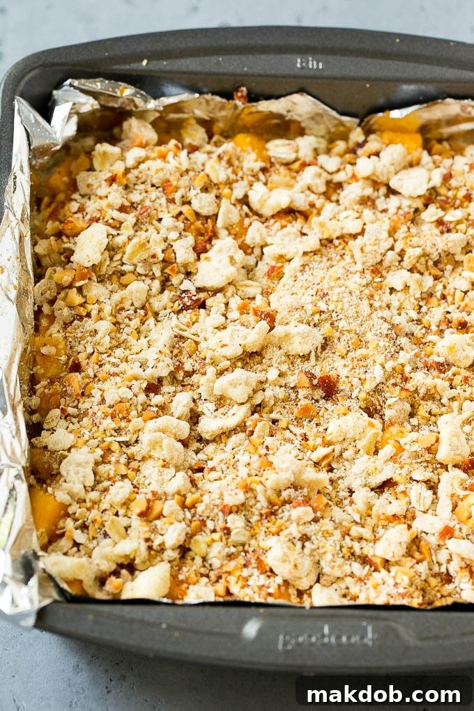 Unbaked Peach Crumble Bars with Streusel A top-down view of a baking pan filled with unbaked peach crumble bars, showcasing the uniform streusel topping before baking to golden perfection.