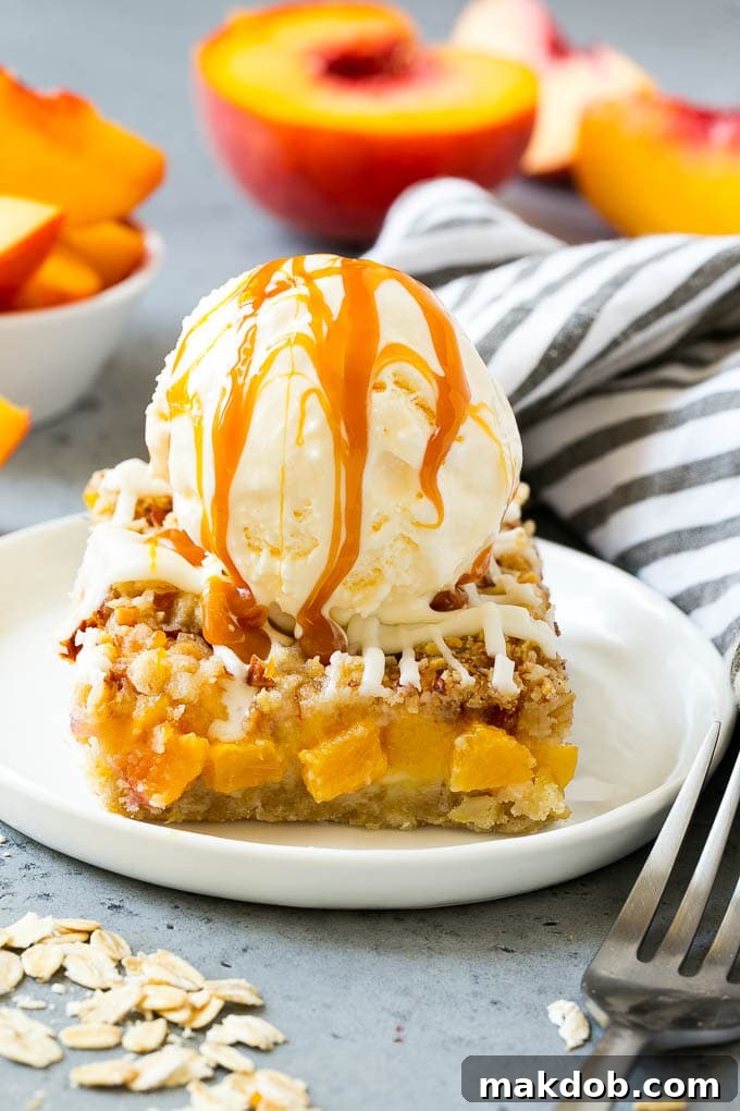 Peach Crumble Bar with Vanilla Ice Cream and Caramel A single, perfectly cut peach crumble bar served on a white plate, elegantly topped with a generous scoop of vanilla ice cream and a luscious drizzle of salted caramel sauce.