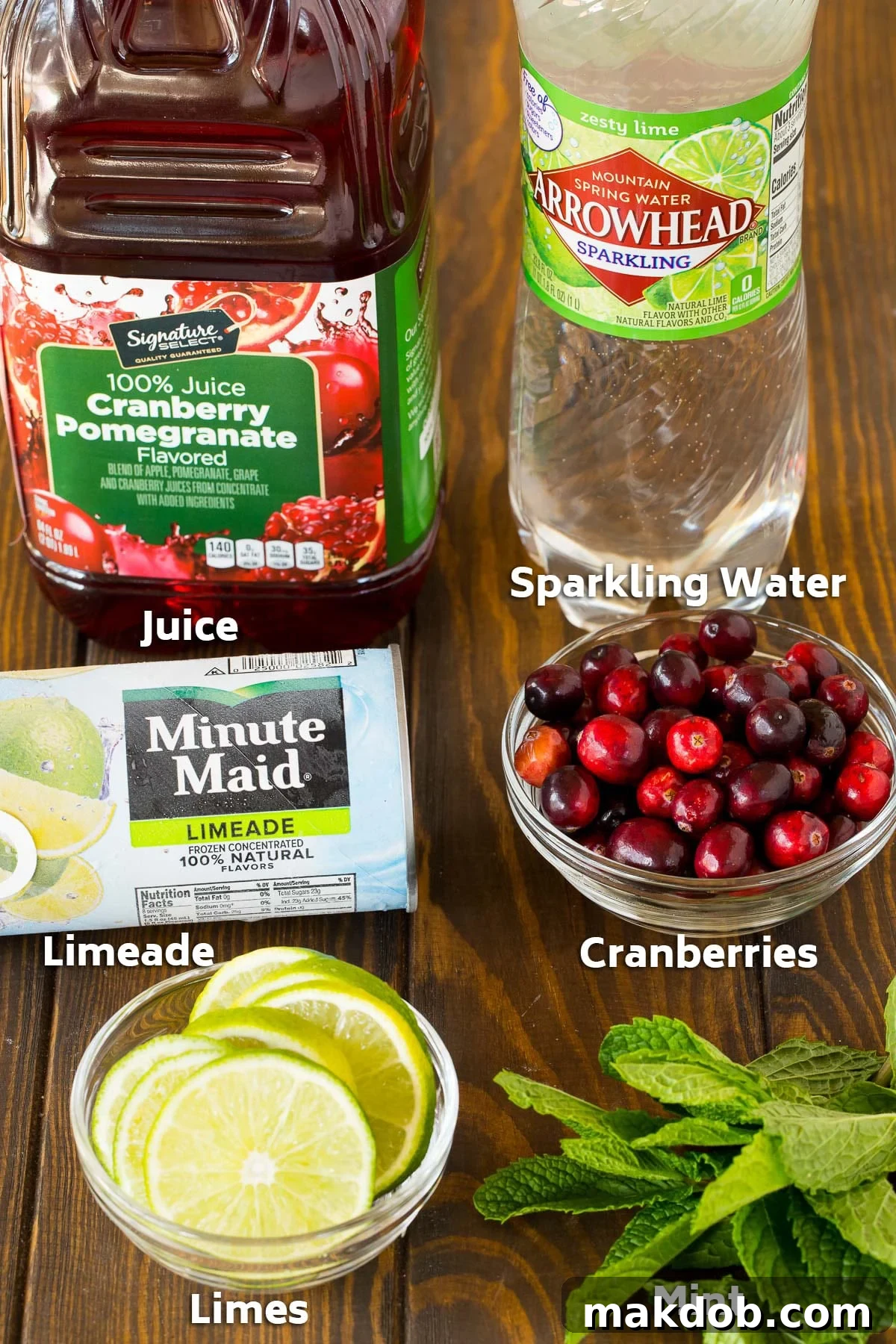Holiday Glow Punch 3 Ingredients for Christmas punch, including fresh limes, mint, cranberries, pomegranate-cranberry juice, and sparkling water.