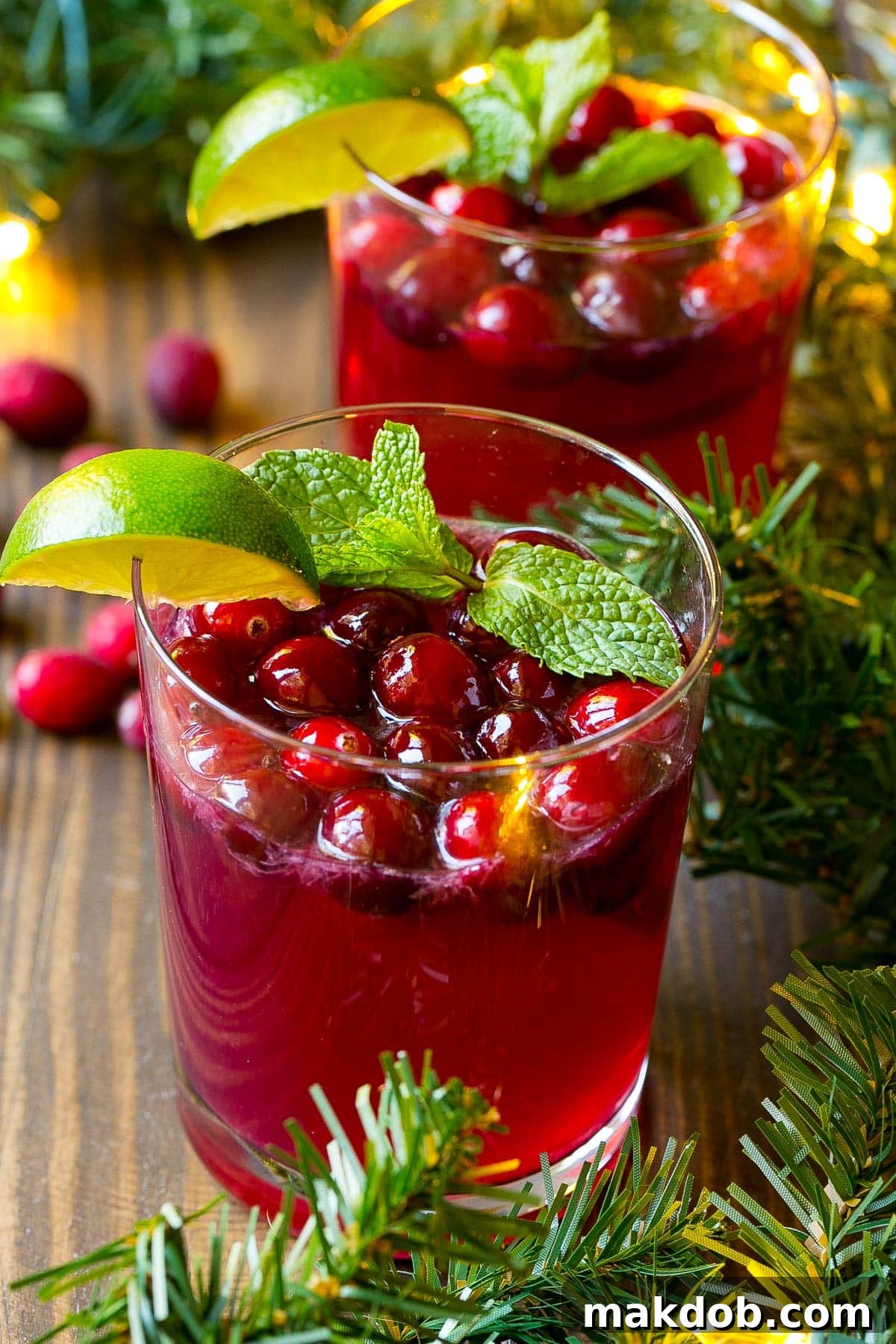 Holiday Glow Punch 5 Individual cups of Christmas punch topped with fresh cranberries, lime slices, and mint sprigs.