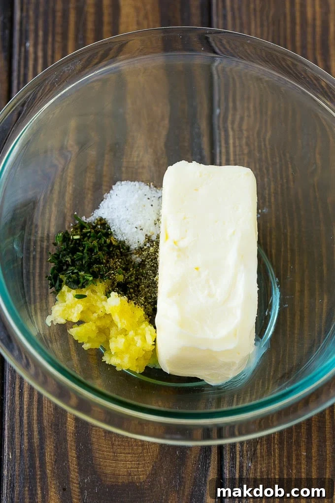 Butter, minced garlic, fresh thyme, and rosemary leaves in a mixing bowl, ready to be combined into the herb butter rub.