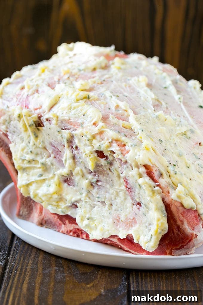 A prime rib roast generously coated in aromatic garlic and herb butter, ready for smoking.