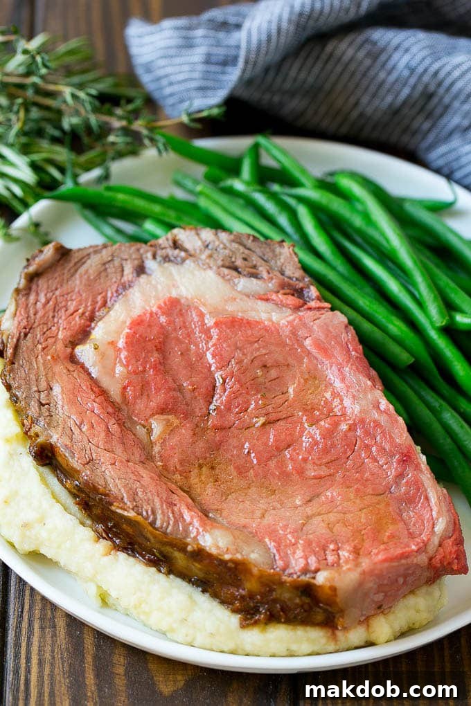 A tender slice of smoked prime rib resting over creamy mashed potatoes, accompanied by vibrant green beans on the side.