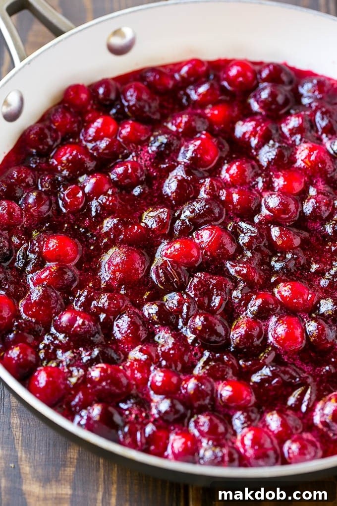 The exquisite texture and color of homemade cranberry sauce captured as it cools, ready to become a holiday favorite. A vibrant close-up of homemade cranberry sauce cooling in a skillet, showcasing its rich texture and color.