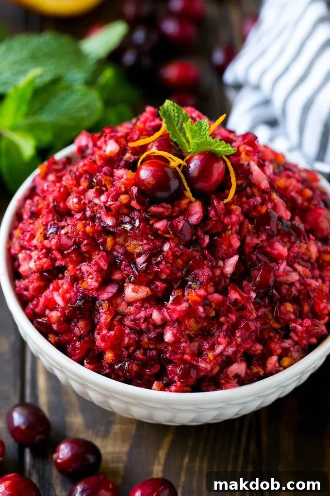 A bowl of cranberry relish topped with whole cranberries, orange zest and mint. Vibrant and fresh, ready for serving.